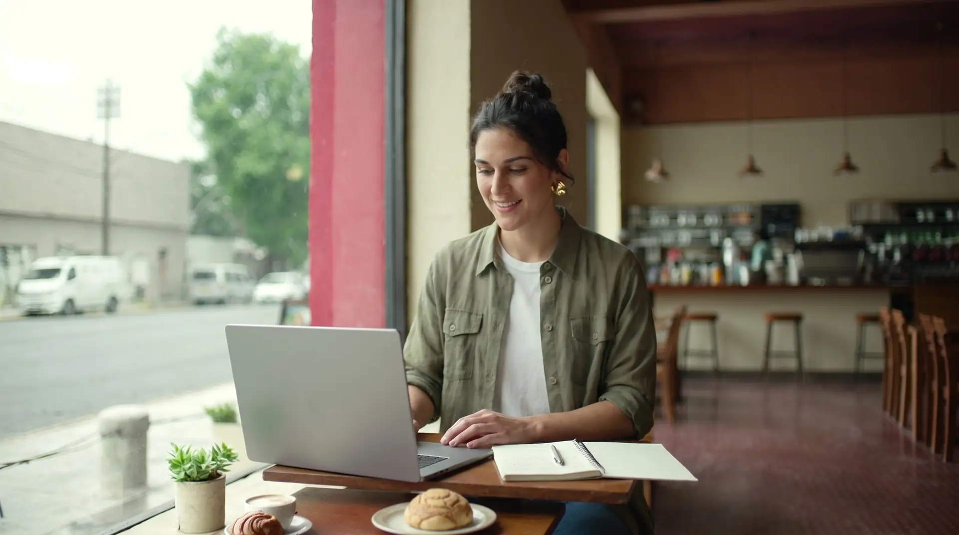 Joven trabajando con su laptop en su proyecto desde una cafetería